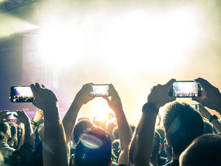 Crowd at a music festival taking a picture with a smartphone.