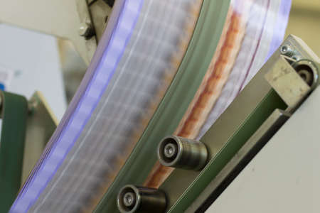 Close up detail of cartographic industrial machinery at work in a production line, conveyor belts are visible, no people are present.の写真素材