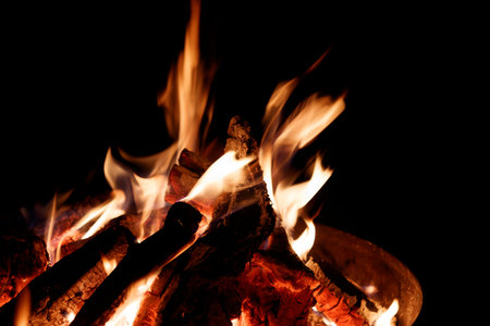 Close-up of a burning firewood in a fireplace on a black background