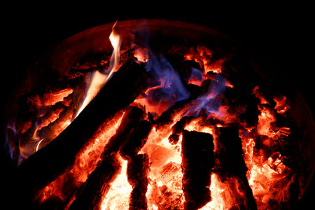 Burning firewood in a fireplace, close-up on a black background