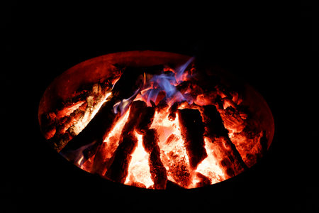 Burning firewood in a brazier on a black background