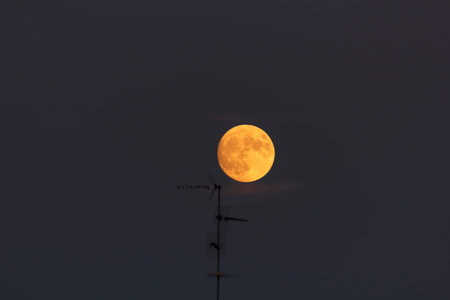 Full blood red moon in a city sky, tv antennas are visible in the foreground. Image shot at 300mm.