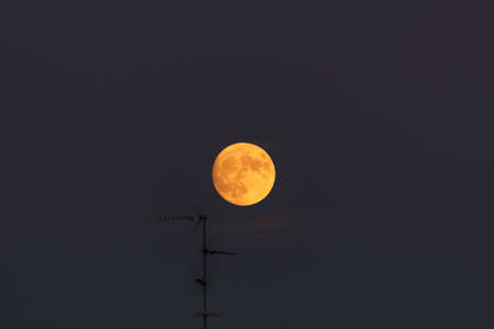 Full moon in the evening sky. The full moon is visible through the clouds.の写真素材