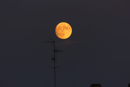 Full blood red moon in a city sky, tv antennas are visible in the foreground. Image shot at 300mm.