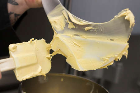 Mixing butter in a metal bowl with a spatula. The process of making butter.の写真素材