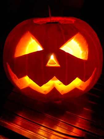 Halloween pumpkin head jack o lantern with burning candle in dark roomの写真素材