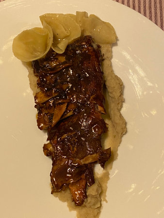 Ribs with potato and sauce on a white plateの写真素材