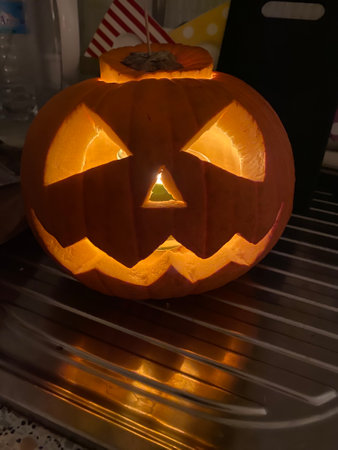 Halloween pumpkin head jack o lantern with burning candle in the darkの写真素材