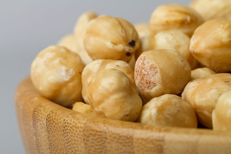 Hazelnuts in a wooden bowl on a white background, top view