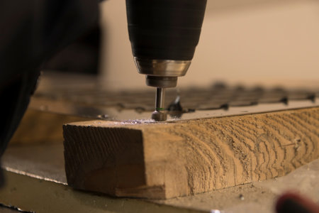 Carpenter drilling a hole in a wooden plank with a milling machineの写真素材