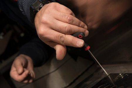 Close-up of a man's hands using a screwdriver.
