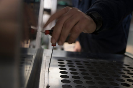 Close-up shot of a man using a screwdriver to cut a metal sheet
