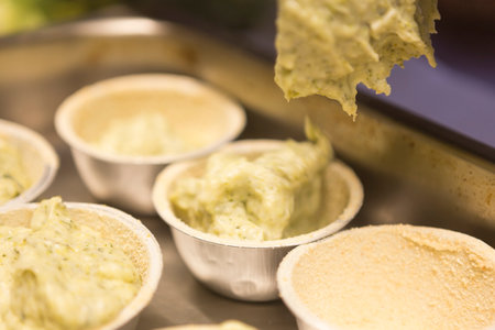 Close up of cheese being poured into a bowl of tartletsの写真素材