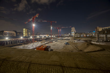 Construction site at night with cranes and buildings in the background.の写真素材