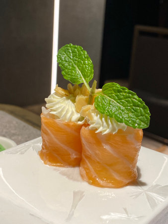 Salmon sushi with cream cheese and mint leaf on white plate.の写真素材
