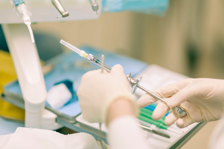 Detail of a dentist performing surgery with anesthesia on a patient for root canal treatment and...