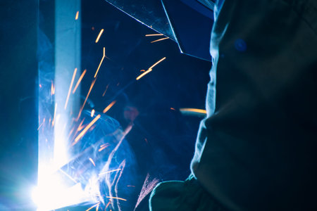 Detail of heavy industry manufacturing, sparks come out of a metal working welder.