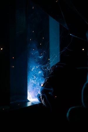 Detail of heavy industry manufacturing, sparks come out of a metal working welder.