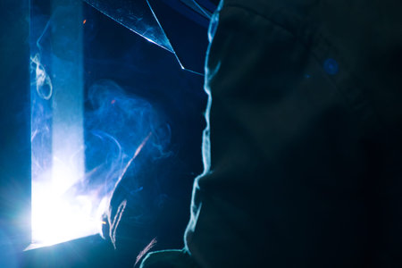 Detail of heavy industry manufacturing, sparks come out of a metal working welder.