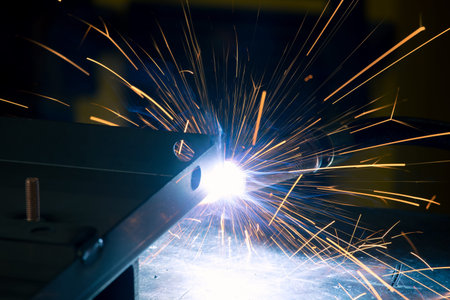 Detail of heavy industry manufacturing, sparks come out of a metal working welder.