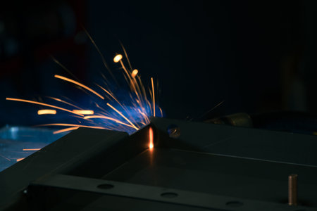 Detail of heavy industry manufacturing, sparks come out of a metal working welder.
