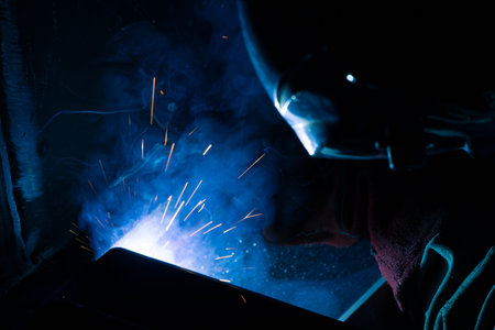 Detail of heavy industry manufacturing, sparks come out of a metal working welder.