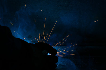 Detail of heavy industry manufacturing, sparks come out of a metal working welder.