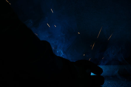 Detail of heavy industry manufacturing, sparks come out of a metal working welder.