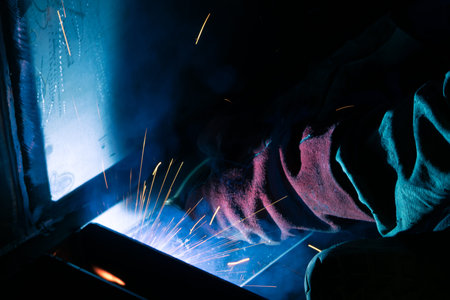 Detail of heavy industry manufacturing, sparks come out of a metal working welder.