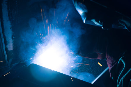 Detail of heavy industry manufacturing, sparks come out of a metal working welder.