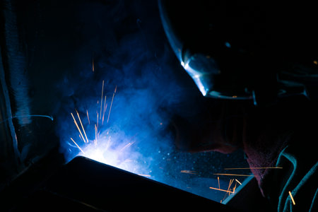 Detail of heavy industry manufacturing, sparks come out of a metal working welder.