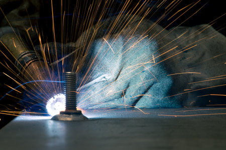 Detail of heavy industry manufacturing, sparks come out of a metal working welder.