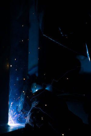Detail of heavy industry manufacturing, sparks come out of a metal working welder.