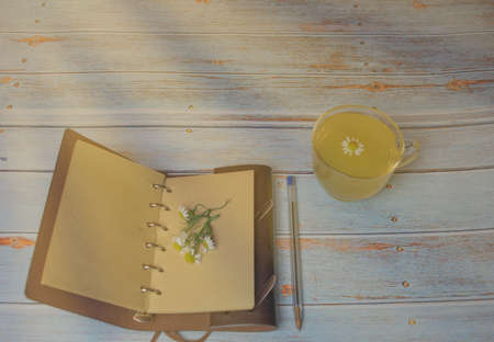 Tea with chamomile flower and open diary with chamomile flowers in romantic concept with sun raysの写真素材