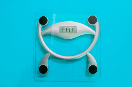 body scale made of glass with the word fat. in yellow backgroundの写真素材