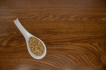 white ceramic spoon with lentils on oak tableの写真素材