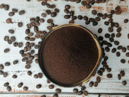 Natural bowl with ground coffee on white wooden table with organic coffee beansの写真素材