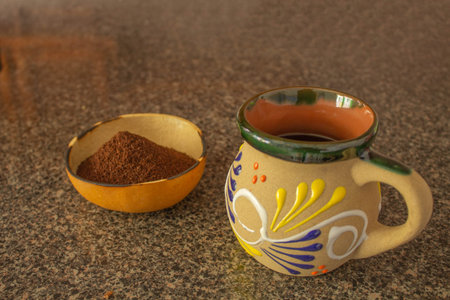 Mexican cup of coffee and craft bowl with ground coffee on marble tableの写真素材