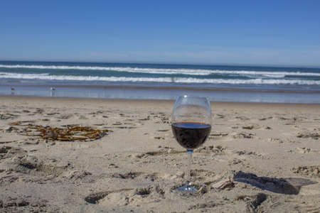 glass of red wine on the sand on the beach overlooking the sea in a romantic atmosphereの写真素材