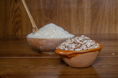 Mexican style clay containers with rice grains and beans on wooden boards with wooden handmade spoonの写真素材