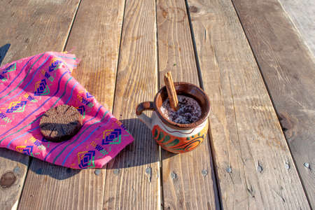 Mexican chocolate champurrado with cinnamon in traditional clay cup and Mexican sarapeの写真素材