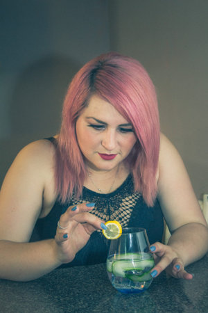 bartender woman preparing refreshing cocktail with cucumber, lemon and vodka