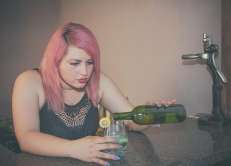 Pink haired woman lying on the bed. using old camera