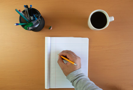 top view of person writing in notebook. Writer
