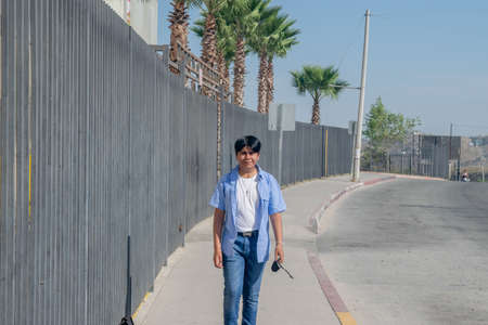 Mexican boy walking on the street, next to palm treesの写真素材