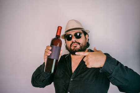 Hispanic man with panama hat showing wine bottle with empty label. Wine bottle mockupの写真素材