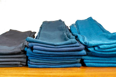 stacks of jeans of different colors. in store on wooden shelfの写真素材