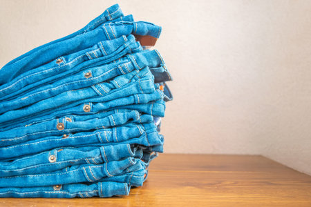 closeup of stack of blue jeans. in store on wooden shelf