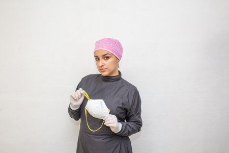 female doctor in surgical suit showing n95 face mask to prevent covid-19