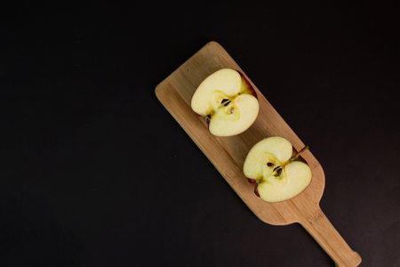 Red apple cut in half on table on black
